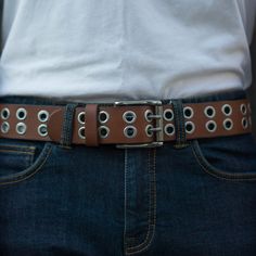 Made from tough leather, this belt features rows of two grommets running down the entire belt. Stylish, secure, and perfect with jeans. The Clash bassist Paul Simonon famously smashed his Fender Precision on stage in the south of London. We may not be that angry, but we're just as passionate when we make our belts. The clothes may make the man, but the look is never complete without the belt. One solid piece of leather. No bonded belts, period. This results in a belt that minimizes stretch and w Paul Simonon, Grommet Belt, Global Supply Chain, Jean Belts, The Clash, Leather Belts, Belt Size, Black Belt, Full Grain Leather