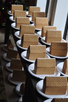 several white plates topped with graham crackers on top of each other in front of a christmas tree