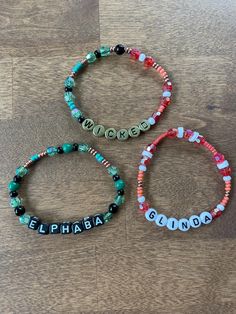 three personalized bracelets on a wooden floor with the word name spelled in different languages