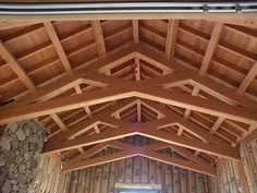 the inside of a large wooden building with stone walls and wood beams on the ceiling