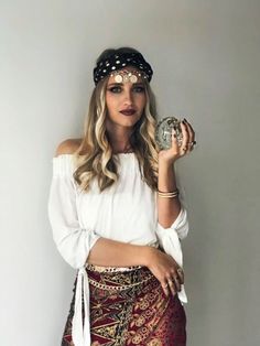 a woman in a white top and red skirt holding a silver coin with her right hand