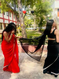 two women dressed in red and black talking on their cell phones, one holding a scarf over her head