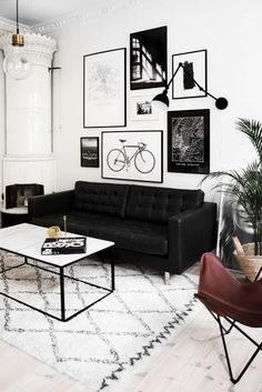 a black and white living room with pictures on the wall, a couch and a coffee table