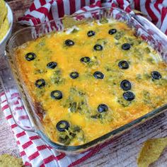 a casserole dish with olives and cheese in it next to some tortilla chips