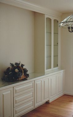 an empty room with white cabinets and a chandelier hanging from the light fixture