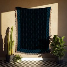 a blue blanket sitting on top of a black and white checkered floor next to a potted plant