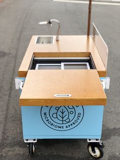 a blue and wooden cart with an umbrella on the top that is attached to it