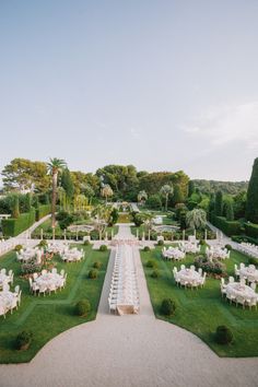 an outdoor wedding set up with white tables and chairs in the middle of a garden