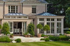 a large house with lots of windows and plants in the front yard, surrounded by greenery