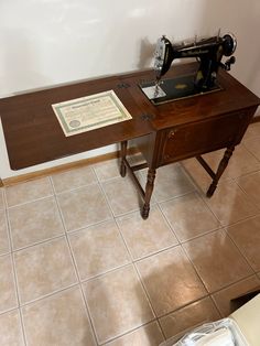 an old sewing machine sitting on top of a wooden table next to a sign that reads