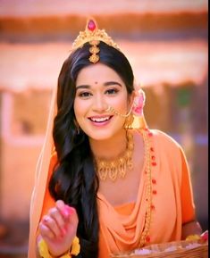 a woman in an orange outfit is smiling and holding a basket with food on it