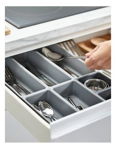 a drawer with utensils and spoons in it that is open to show the contents