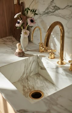 a marble sink with gold faucets and flowers