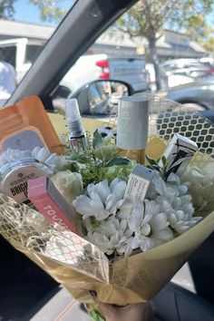 a bouquet of flowers sitting in the back seat of a car with cosmetics on it