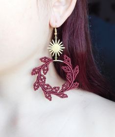 a close up of a person wearing earrings with leaves on the back of their ear