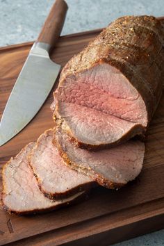 sliced meat sitting on top of a cutting board next to a knife