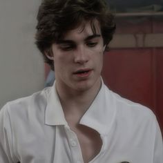 a young man wearing a white shirt looking at his cell phone