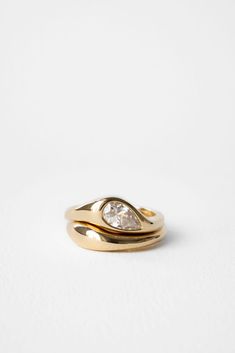 a gold ring with two pear shaped diamonds on the top and bottom, set against a white background