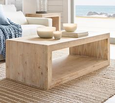 a living room with a couch, coffee table and ocean view