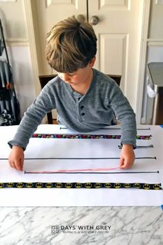 a little boy that is sitting at a table with some tape on it and writing