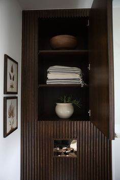 a wooden cabinet with towels and pictures on the wall