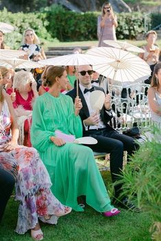 a group of people sitting around each other on lawn chairs with umbrellas in front of them