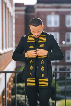 a man in black and yellow is standing on a balcony looking down at his jacket