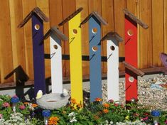 colorful birdhouses are lined up in a flower bed