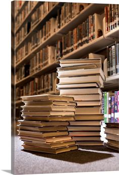 a pile of books sitting on the ground in front of a book shelf full of books