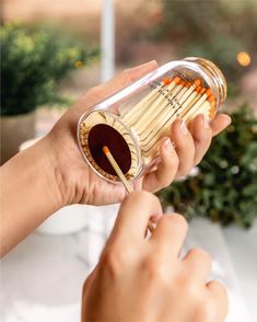 a person holding a glass jar with chopsticks in it and another hand reaching for the top