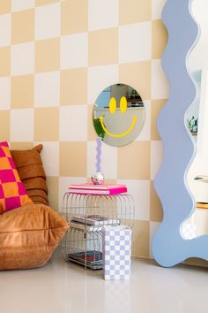 a living room with a smiley face on the wall next to a chair and mirror