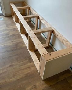 a wooden shelf sitting on top of a hard wood floor next to a wall and window