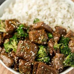 beef and broccoli with white rice in a bowl on a wooden table top