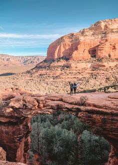 two people standing on the edge of a cliff