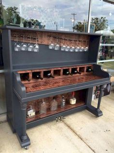 an old piano with wine glasses on the top and bottom shelf in front of it