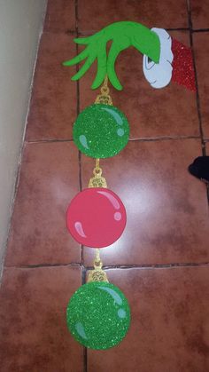 the grin face is hanging from a string with green and red decorations on it's side