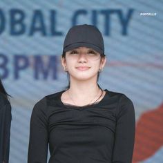 a woman standing in front of a sign wearing a black shirt and hat with the words global city on it