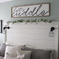 a bed with white sheets and pillows under a sign that says let's cuddle