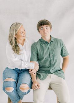 a man and woman sitting on top of a wooden chair with their arms around each other