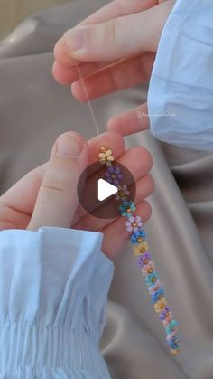 a person is holding something with beads on it's string and the video appears to be playing