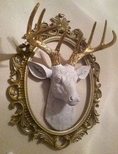 a deer head mounted to the side of a wall in a gold frame with ornate details