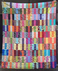 a multicolored quilt hanging on the side of a building