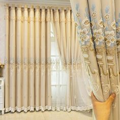 the curtains in this living room are decorated with blue and white flowers