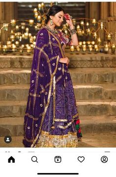 a woman in a purple and gold sari standing on steps with lights behind her