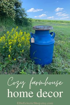 a blue barrel sitting in the middle of a field next to yellow flowers and grass