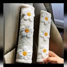 two white crocheted flowers are sitting in the back seat of a car, one with yellow centers