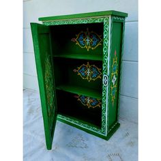 a green cabinet with ornate designs painted on it