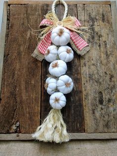 a bunch of white pumpkins are hanging on a wooden door hanger with burlap