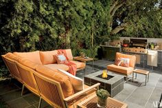 an outdoor living area with couches, tables and grill