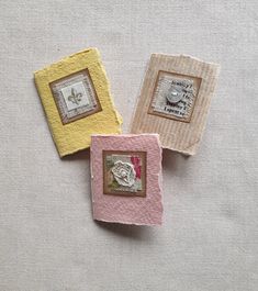 three small square pieces of fabric sitting on top of a white cloth covered tablecloth